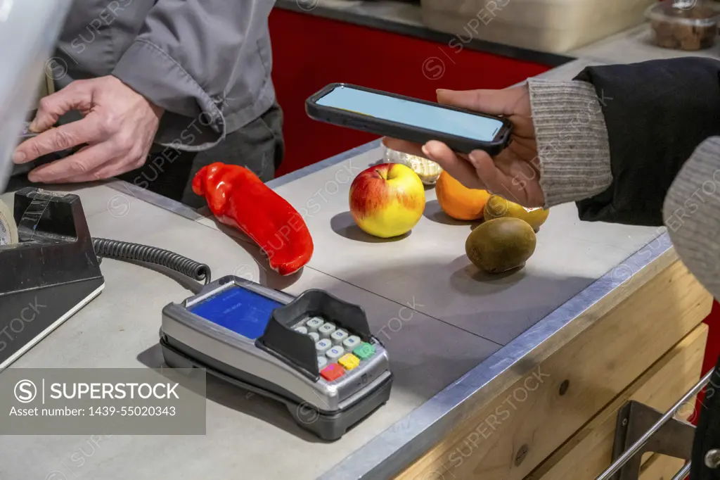 Adult female paying for fruit and vegetables.