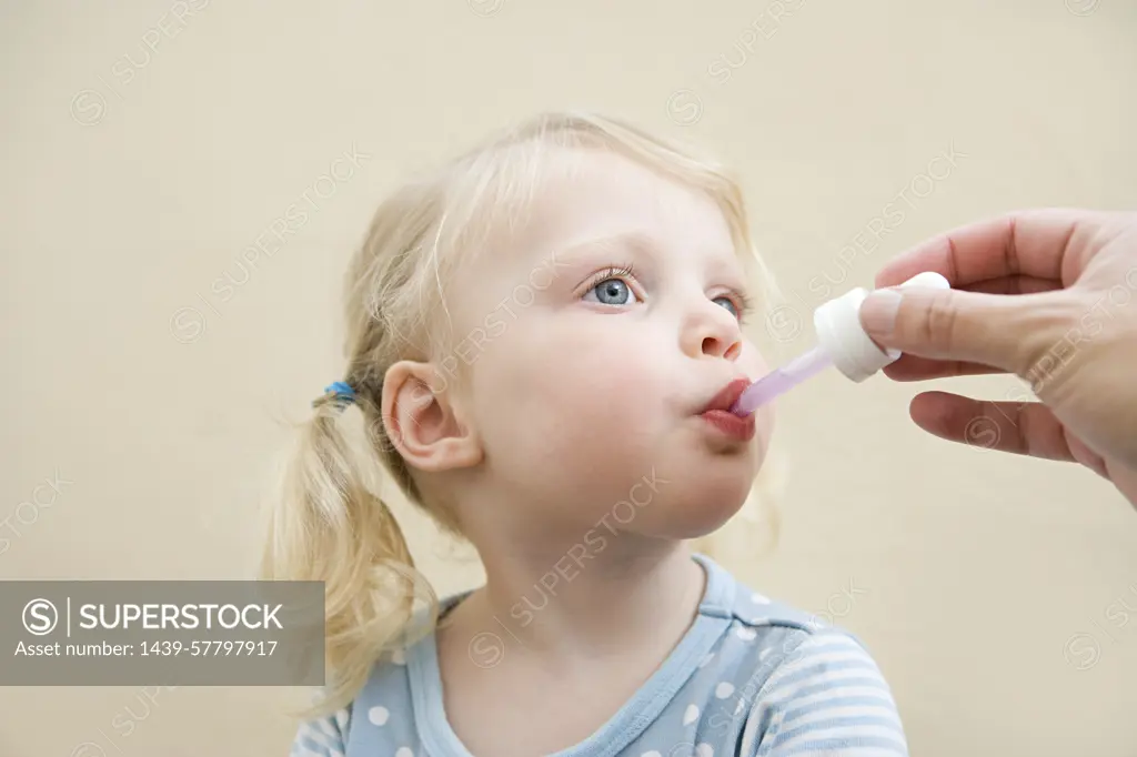 Young child receiving medicine from a dropper