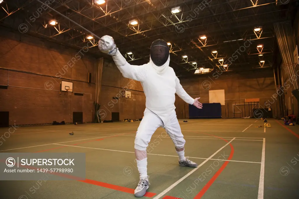 Fencer in midlunge at the gymnasium ready for competition