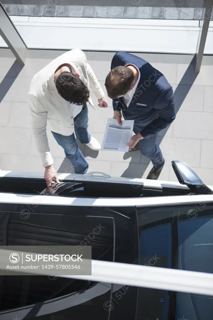 Overhead view of salesman and customer looking at new car in car dealership