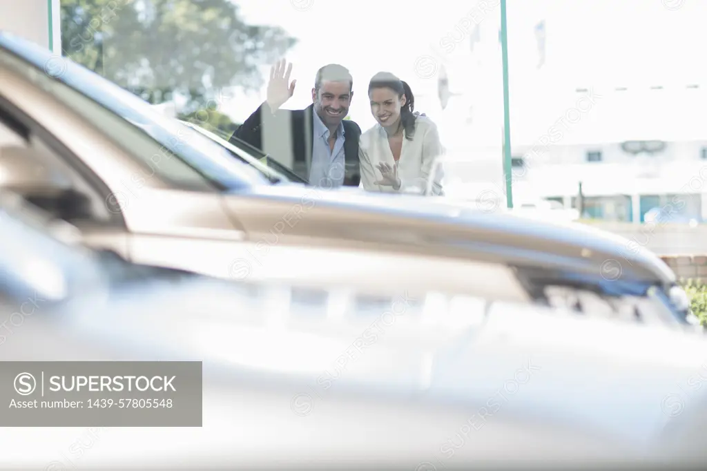 Mid adult couple looking through car dealership window