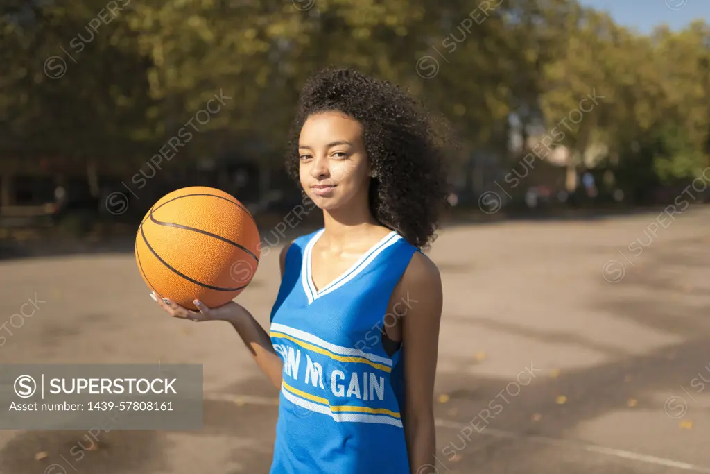 Portrait young female basketball player holding up basketball