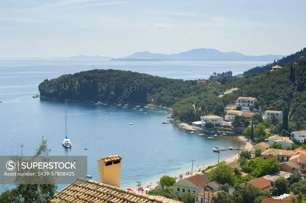 View of coastal village rooftops and bay, Corfu, Greece