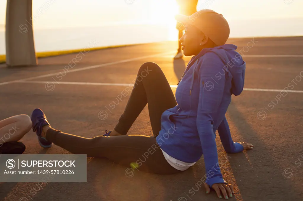 Young woman sitting on basketball court, outdoors