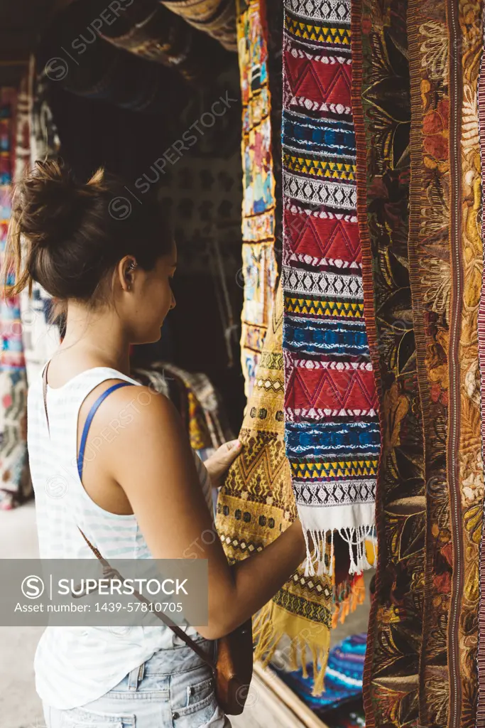 Young woman shopping for textiles at market stall,  Lake Atitlan, Guatemala