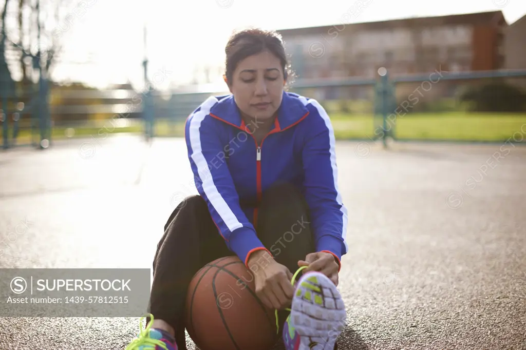 Mature female basketball player tying trainer laces