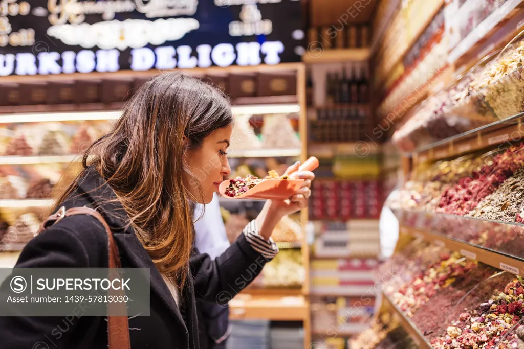 Young woman smelling food in market, Istanbul, Turkey