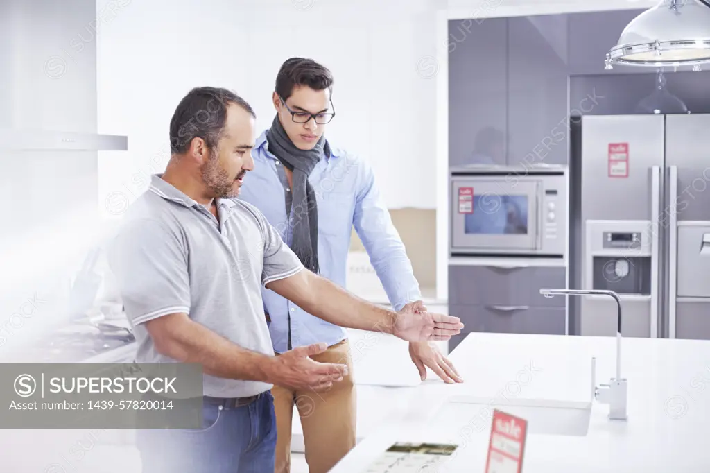 Salesman and young man in kitchen showroom