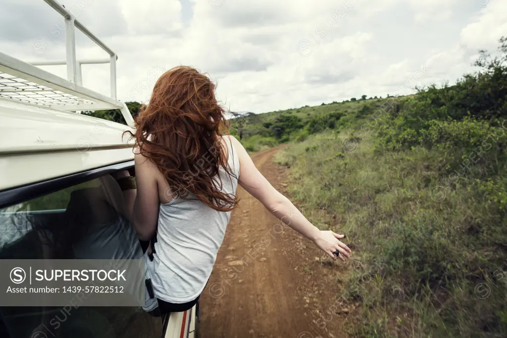 Woman sitting on door of vehicle in wildlife park, Nairobi, Kenya