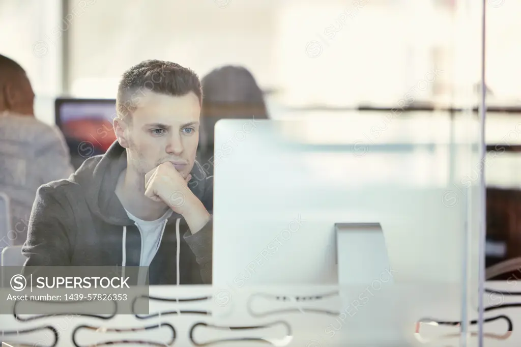 University student working at computer behind glass partition