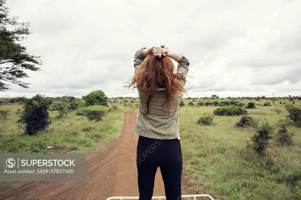 Woman enjoying ride on top of vehicle in wildlife park, Nairobi, Kenya