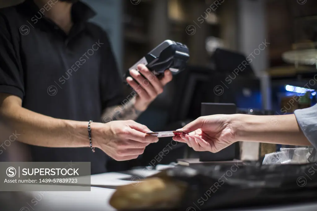 Close up of barista handing credit card to female customer