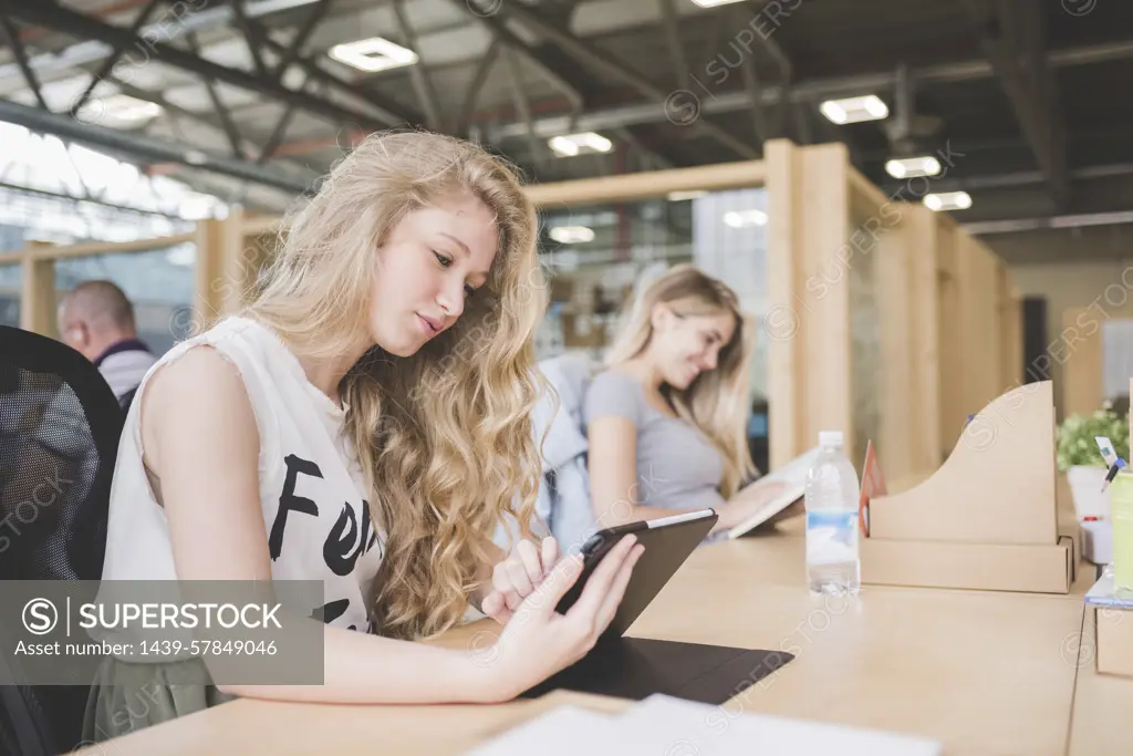 Co-workers working on digital tablet in open plan office