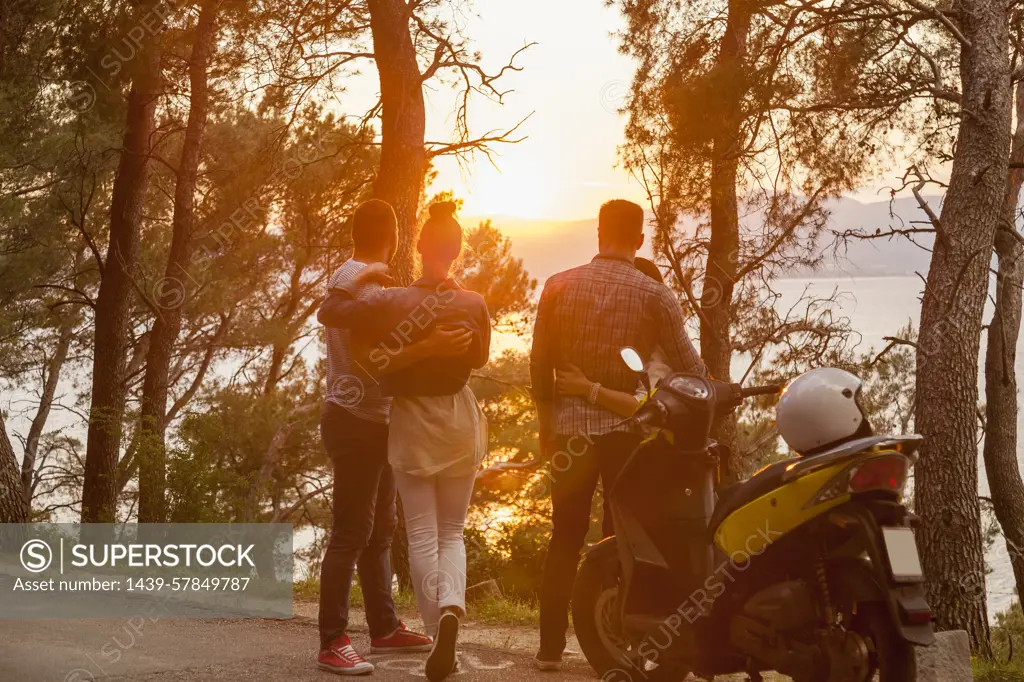 Two moped couples looking out at sunset from coastal road, Split, Dalmatia, Croatia