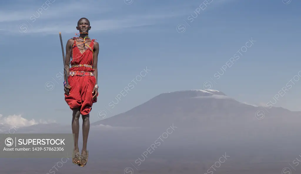 Masai man with traditional dress jumping in front of Mount Kilimanjaro, Amboseli, Rift Valley, Kenya