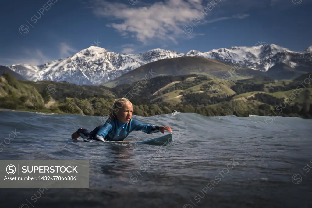 Young boy paddling on surfboard in sea, Kaikoura, Gisborne, New Zealand