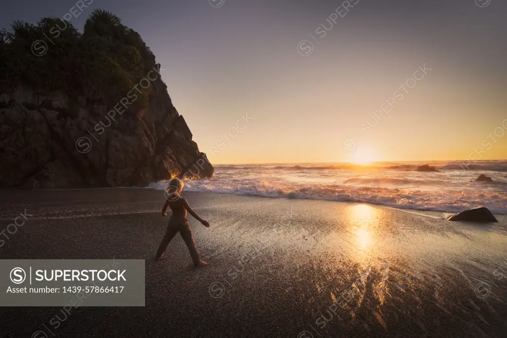 Boy standing on beach, looking at sunset, Kaikoura, Gisborne, New Zealand