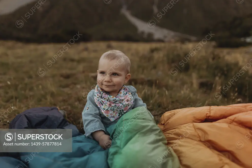 Baby sitting among jackets in wilderness, Wanaka, Taranaki, New Zealand