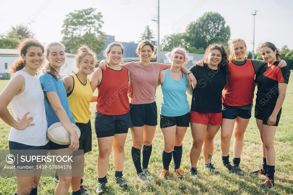 A diverse team of female athletes posing together with confidence on the field.