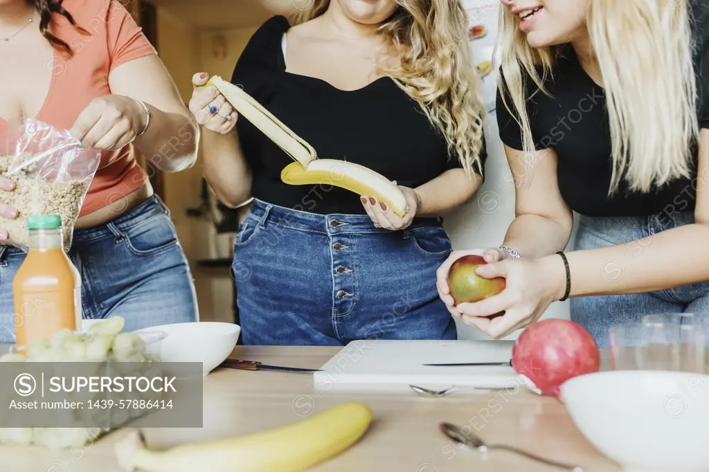 Friends sharing a fun moment while preparing a healthy meal together.