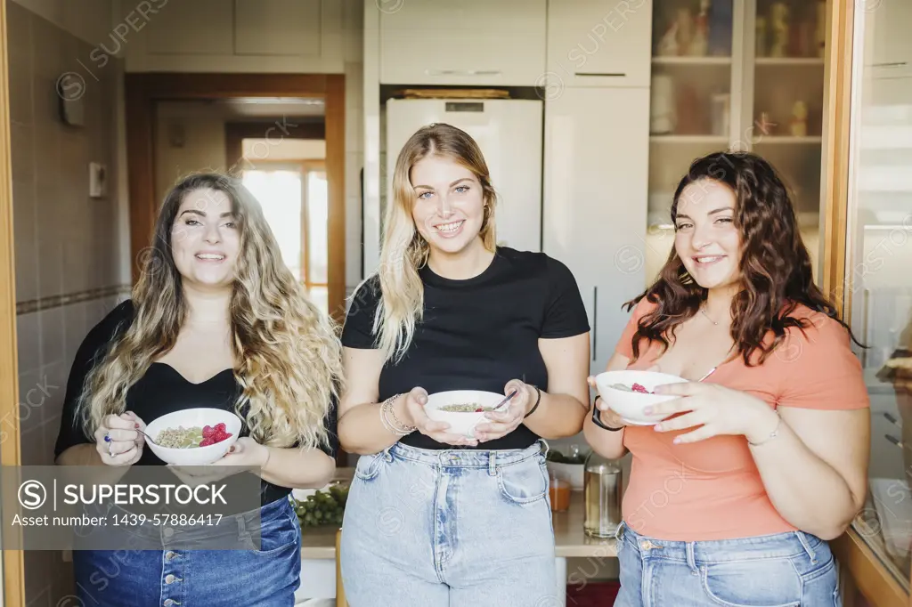 Three friends enjoying a healthy snack in the kitchen.