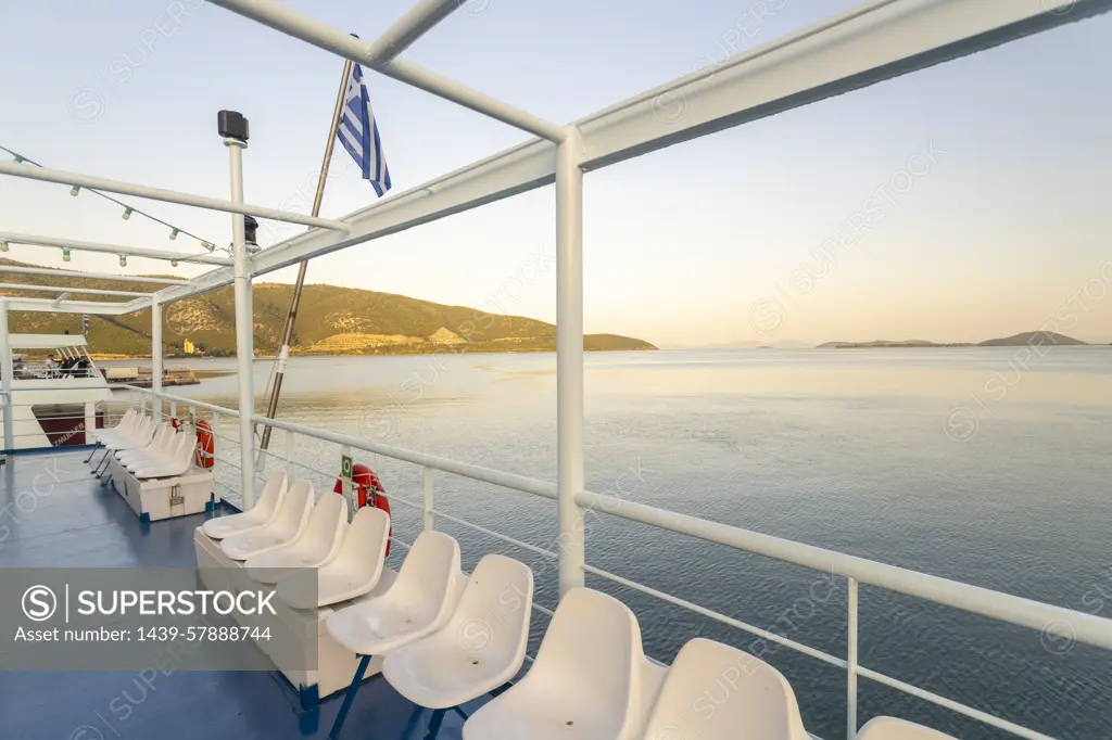 Greece, Igoumenitsa, Row of seats on ferry deck in sea at sunrise