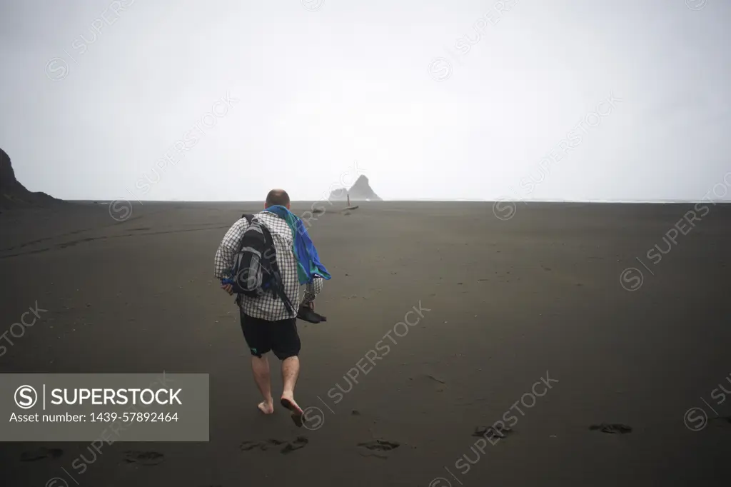 Man walking on Karekare beach, Karekare, New Zealand