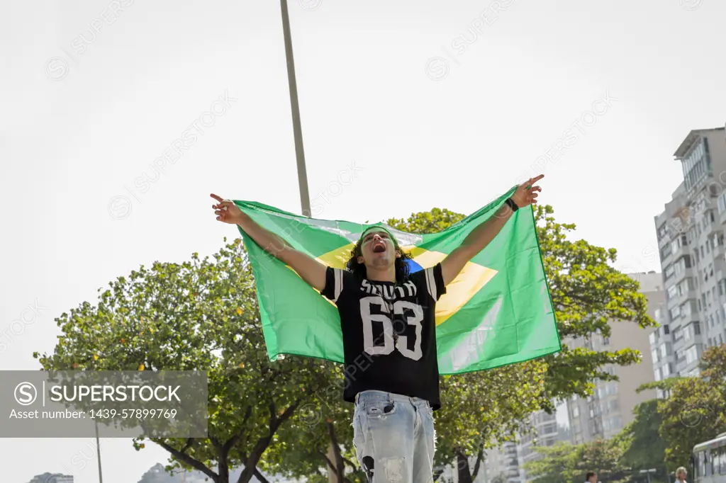 Young man holding up Brazilian flag, Copacabana, Rio De Janeiro, Brazil