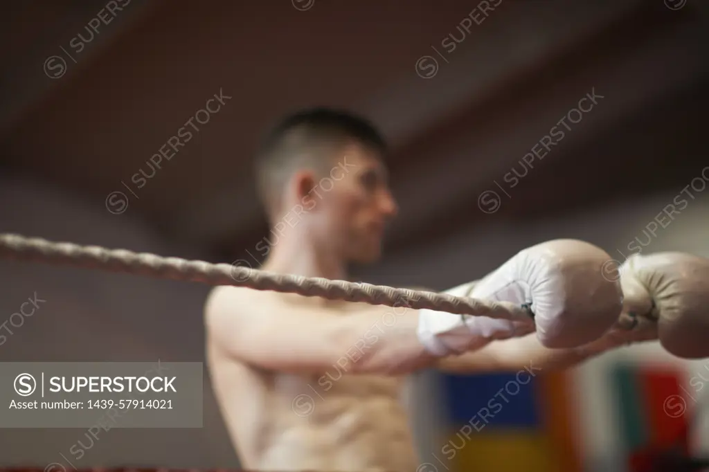 Boxer leaning on ropes of boxing ring