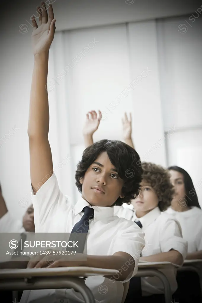 Eager student raising hand in a classroom setting.