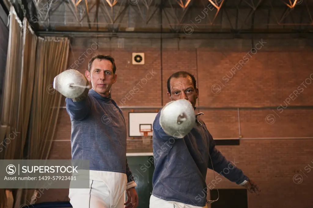 Two fencers pose with epees ready for a match.