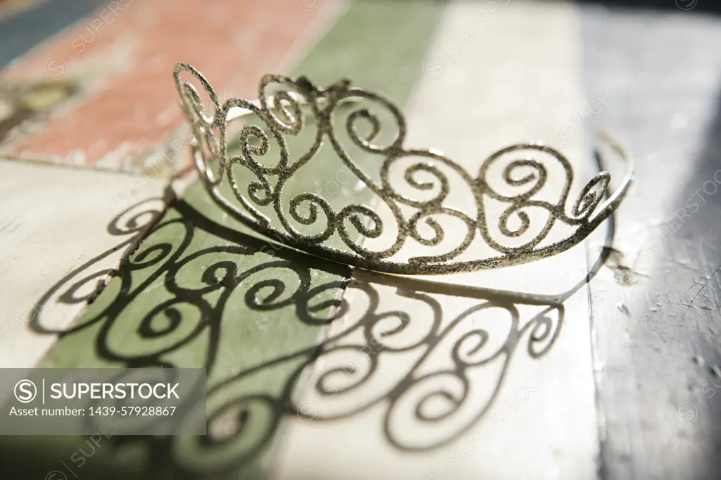 A delicate filigree crown resting on a rustic wooden surface painted with the colors of the Italian flag