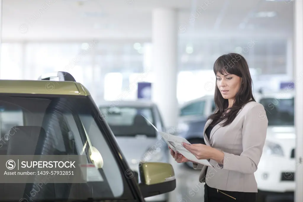 Mid adult woman checking car brochure in showroom