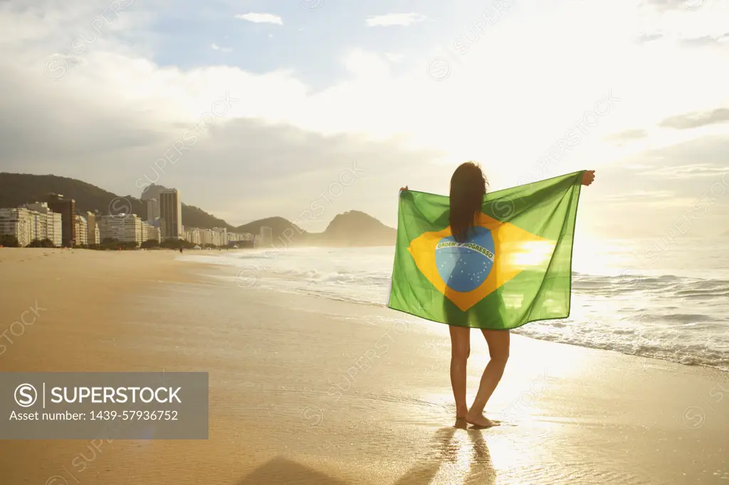 Woman holding Brazilian flag on Copacabana Beach, Rio, Brazil