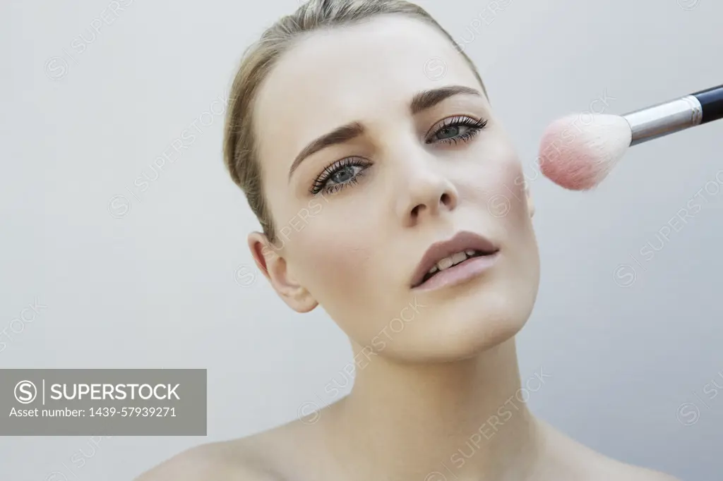 Makeup artist applying blush on a model's cheek