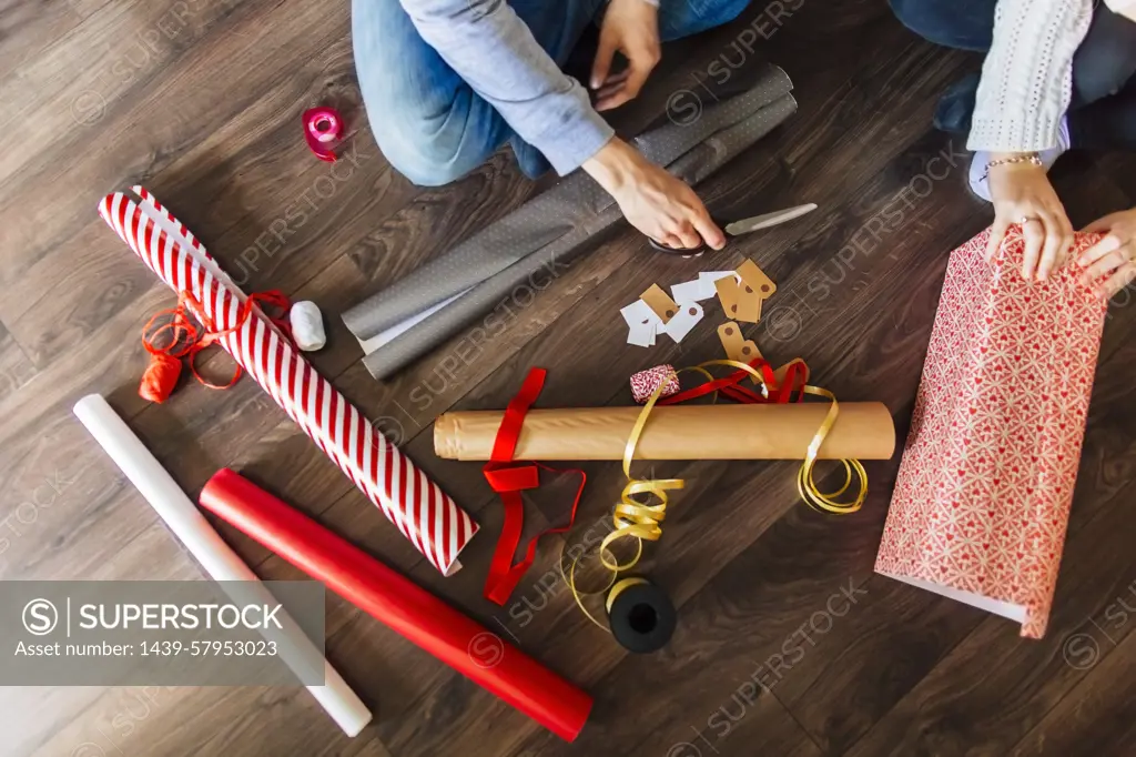 Busy hands wrap holiday gifts with festive paper and ribbon