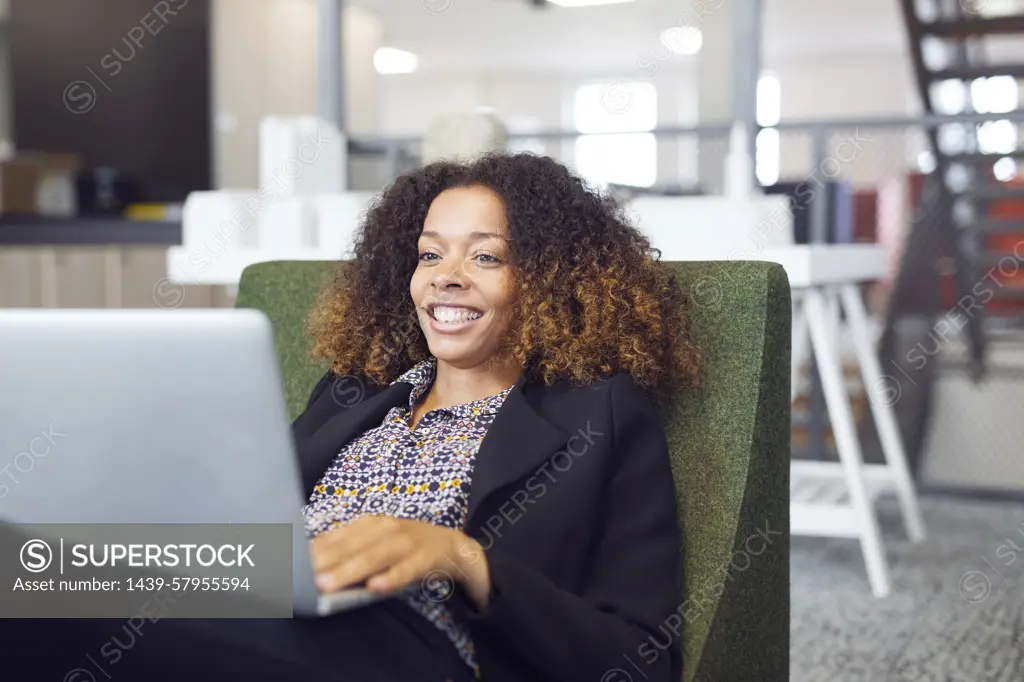 Smiling woman working on laptop in a modern office space