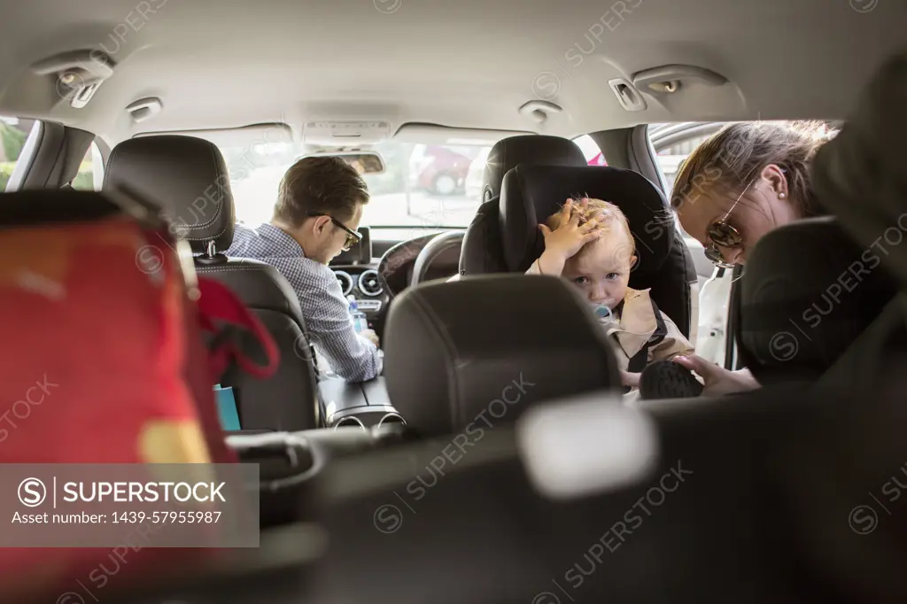 Family moment on a car ride with toddler looking curiously at the camera.