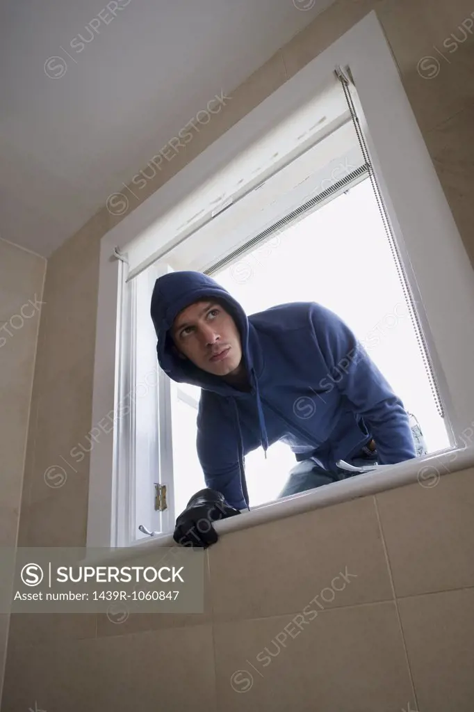 A burglar climbing through a window