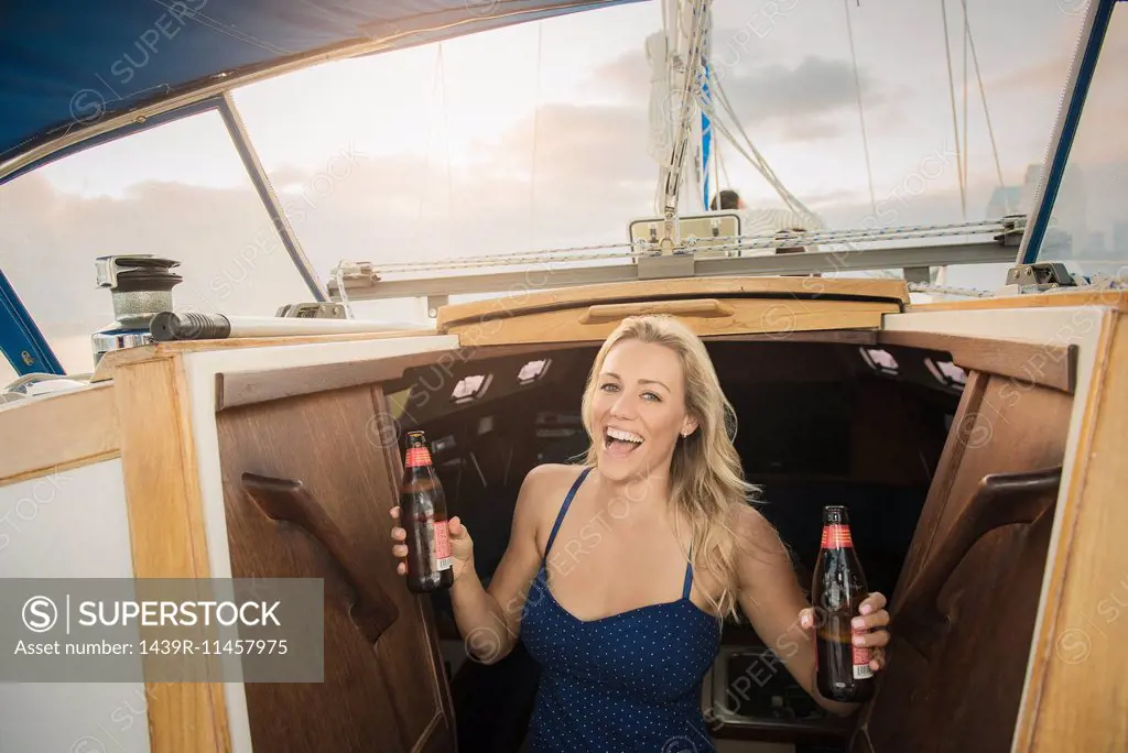 Young woman on sailing boat holding beer bottles