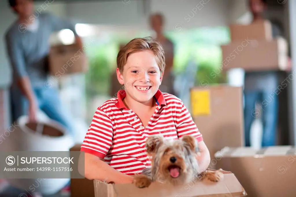 Boy moving house with dog in box