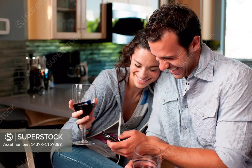 Young couple holding wine glass and looking at mobile phone