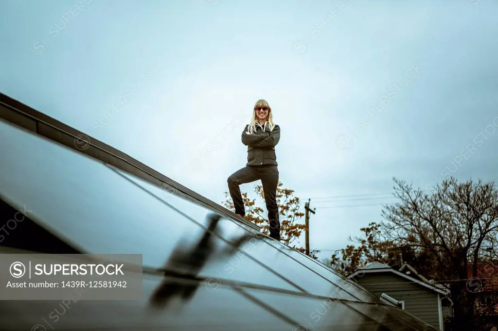 Portrait of mid adult woman standing on newly solar paneled house roof