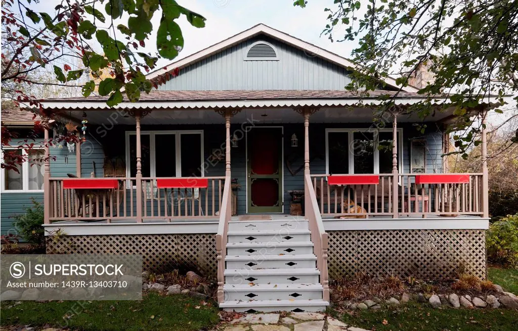 Grey country cottage style home facade with veranda in autumn, Quebec, Canada