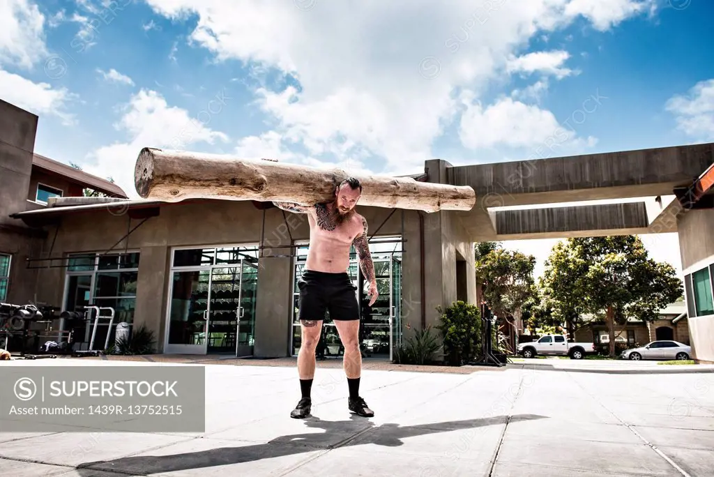 Man carrying log on shoulders outdoors