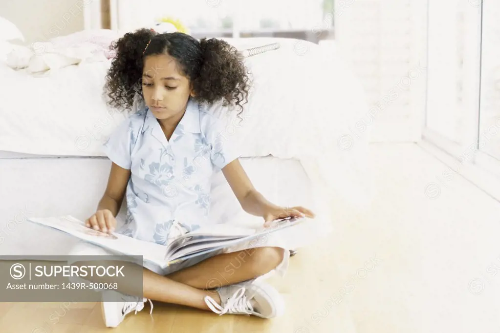 Girl reading against bed