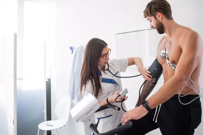 Nurse performing ECG test on patient in consultation room