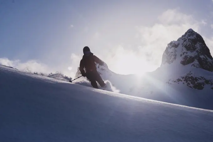 Silhouetted skier skiing downhill, low angle view, Squamish, British Columbia, Canada