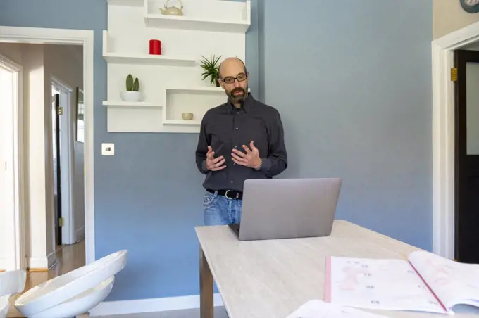 UK, Surrey, Man having virtual meeting via laptop at home