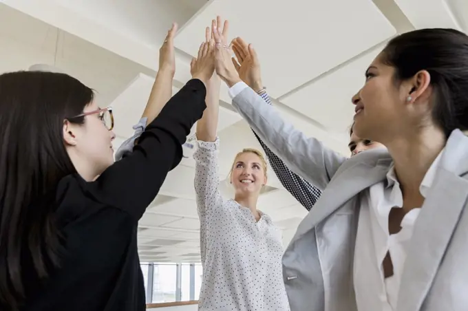 Germany, Bavaria, Munich, Business people doing high-five together in office